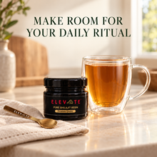 Elevate Shilajit Resin and gold spoon beside warm tea in the 12oz Classic Double Wall Glass Mug.