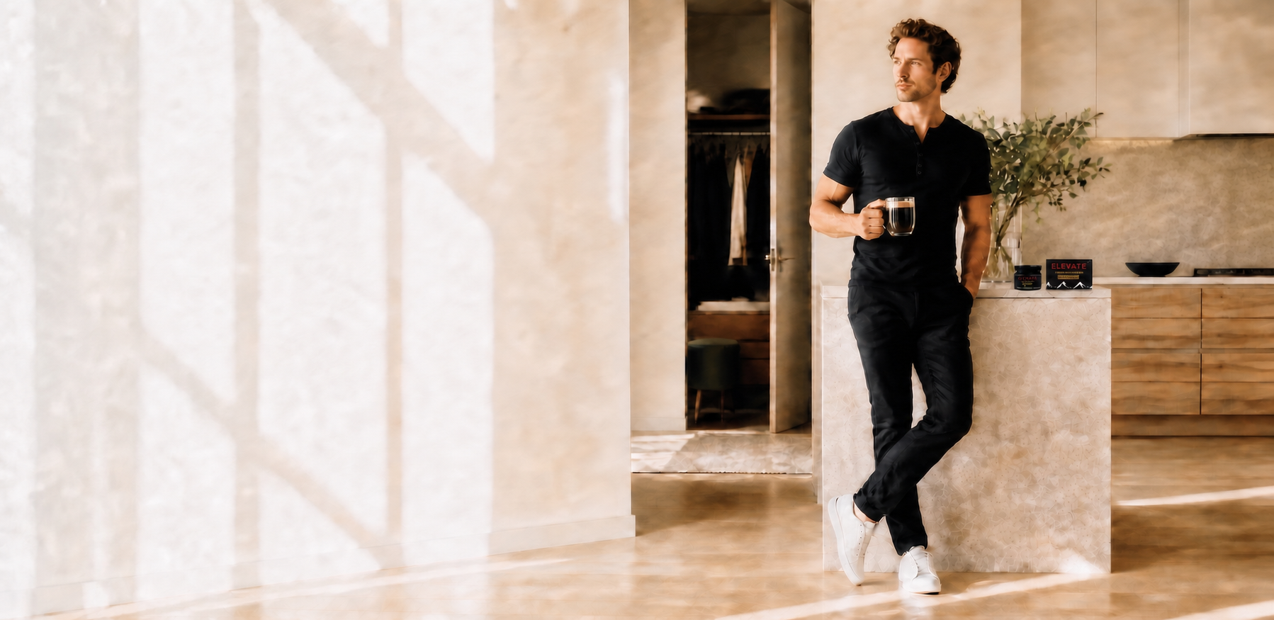 A relaxed morning scene with a black Strovon Henley, white sneakers, a double-wall mug on the counter, and Elevate shilajit